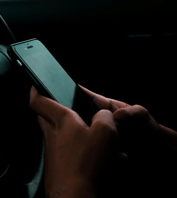 a person using a cell phone in a car, by Carey Morris, pexels, happening, vantablack chiaroscuro, simple detail. greenish lighting, square, bl