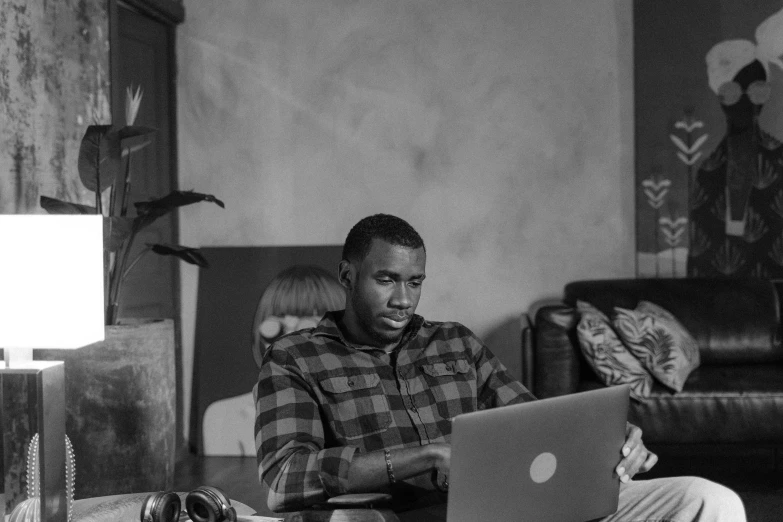 a man sitting on a couch using a laptop computer, a black and white photo, by Daniel Gelon, pexels, realism, frank ocean, lawther sit at table playing dnd, working on her laptop, carson ellis