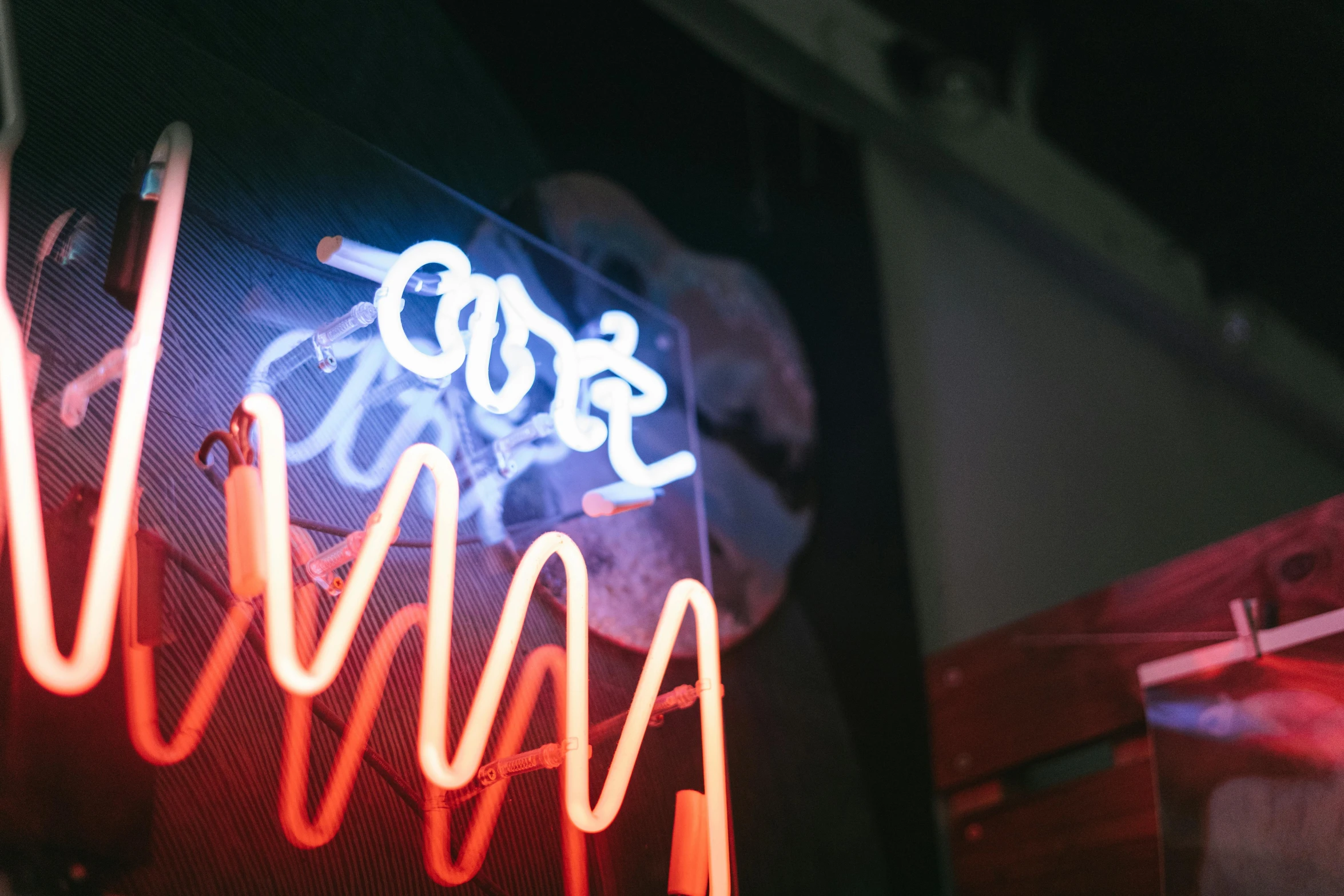 a neon sign hanging from the side of a building, up-close, currents, more, josh grover