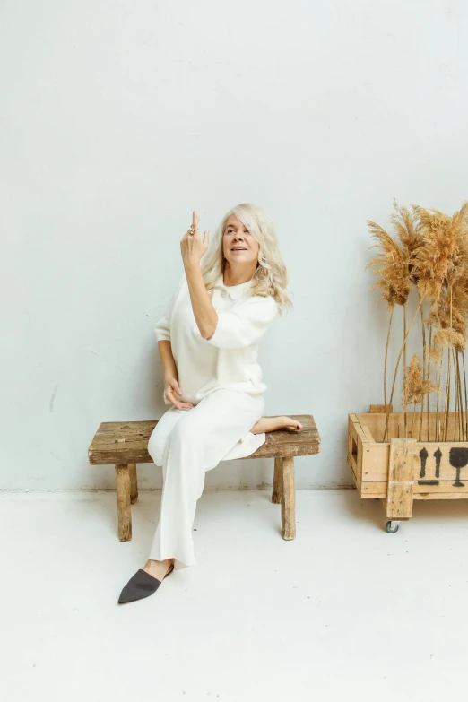 a woman sitting on top of a wooden bench, by Sara Saftleven, minimalism, white hair color, pointing, abcdefghijklmnopqrstuvwxyz, 5 5 yo