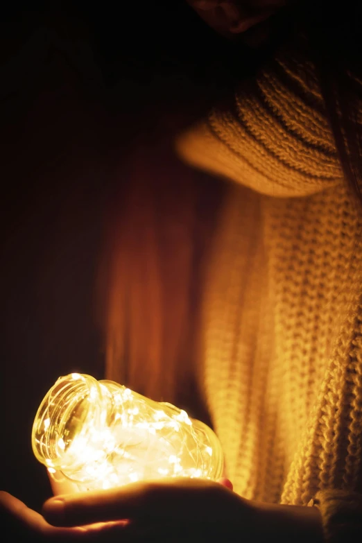 a person holding a light in their hand, trending on pexels, chilly, looking seductive, glowing jar, ( ( photograph ) )