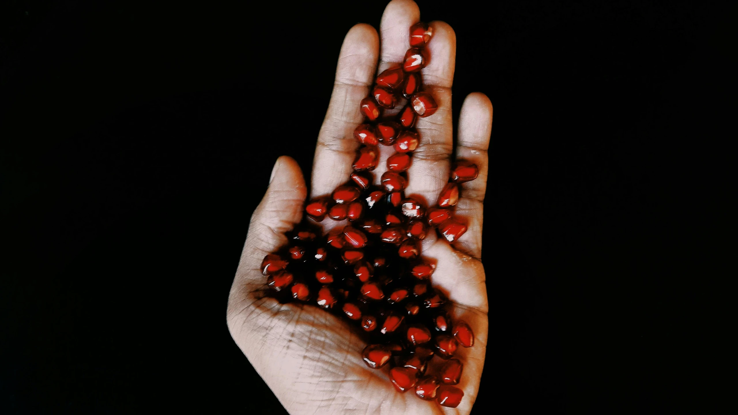 a person holding a handful of pomegranates in their hand, by Julia Pishtar, hurufiyya, made of baked beans, indigenous art, (night), coral red