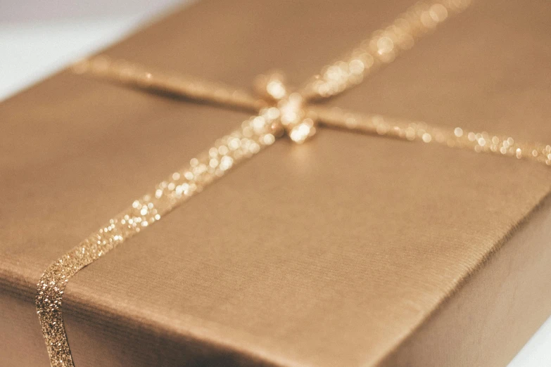 a brown gift box sitting on top of a white table, pexels contest winner, shiny gold background, zoomed in, unedited, less detailing