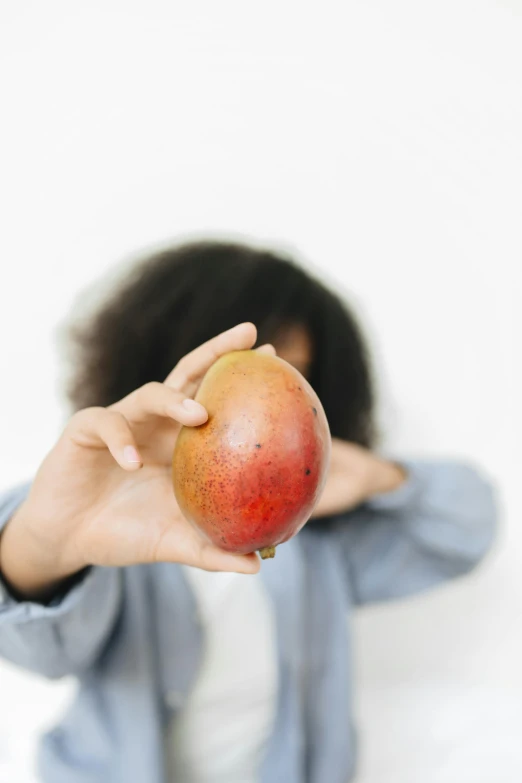 a woman holding an apple in front of her face, an album cover, by Gavin Hamilton, pexels contest winner, mango, 🐿🍸🍋, kiwi fruit, sza