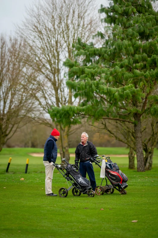 a couple of men standing next to each other on a field, clubs, profile image, peter marlow photography, talking