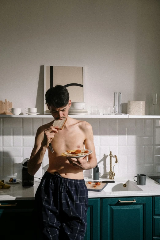 a man standing in a kitchen holding a plate of food, a photo, by Jessie Alexandra Dick, unsplash, hyperrealism, wearing nothing, eating pizza, thin young male, simone graci