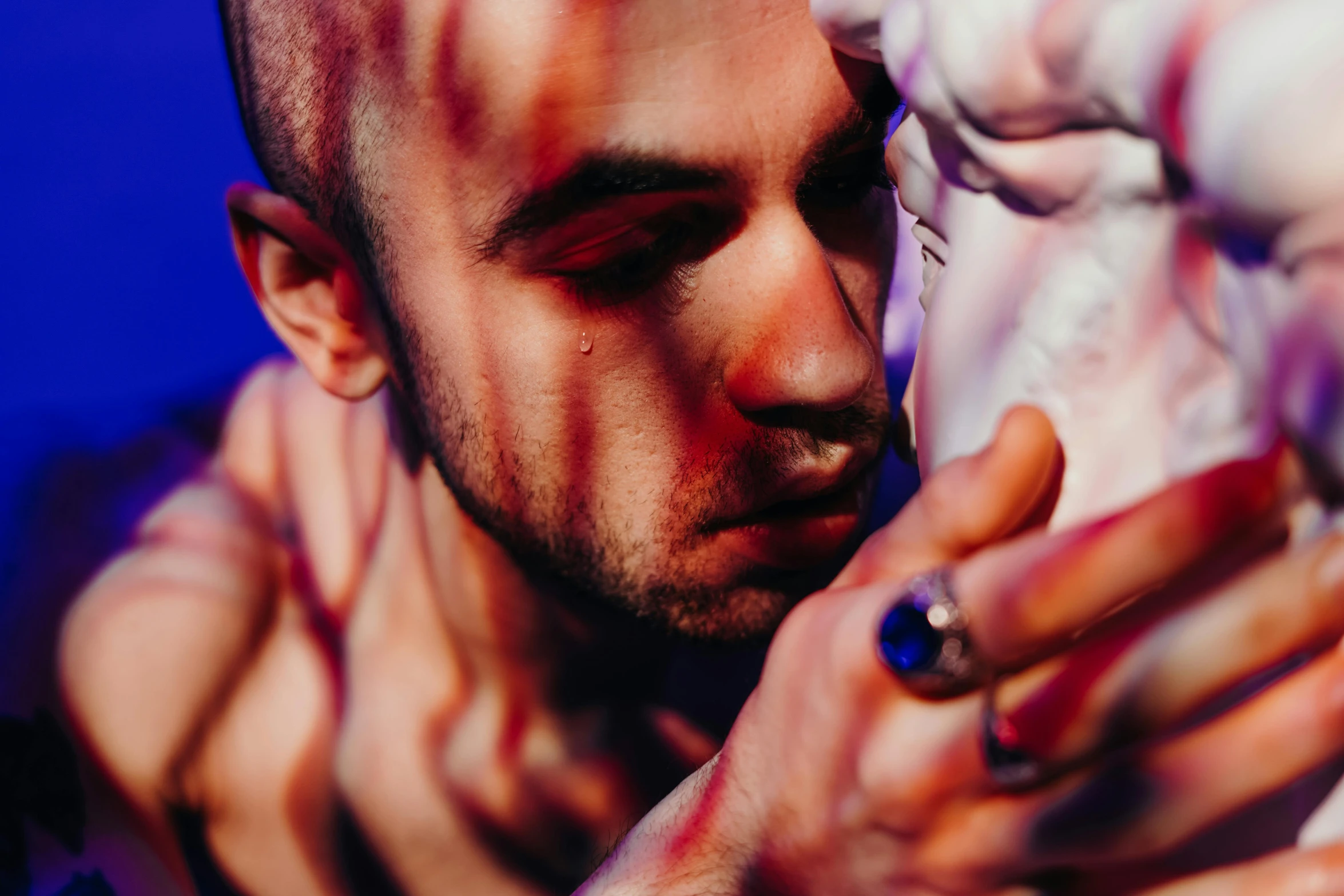 a close up of a person holding a statue, a tattoo, pexels contest winner, bisexual lighting, scars on his face, light red and deep blue mood, gaspar noe