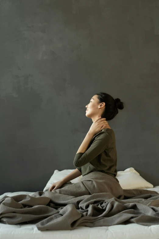 a woman sitting on top of a bed covered in blankets, trending on pexels, renaissance, bendover posture, neck, on a gray background, square