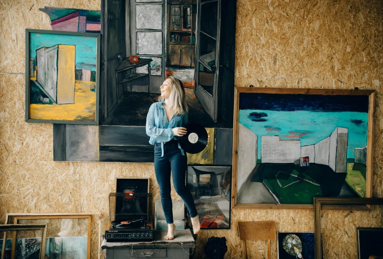 a woman standing on top of a table in front of a painting, by Julia Pishtar, pexels contest winner, standing on a shelf, with a bunch of stuff, 15081959 21121991 01012000 4k, portrait of a big