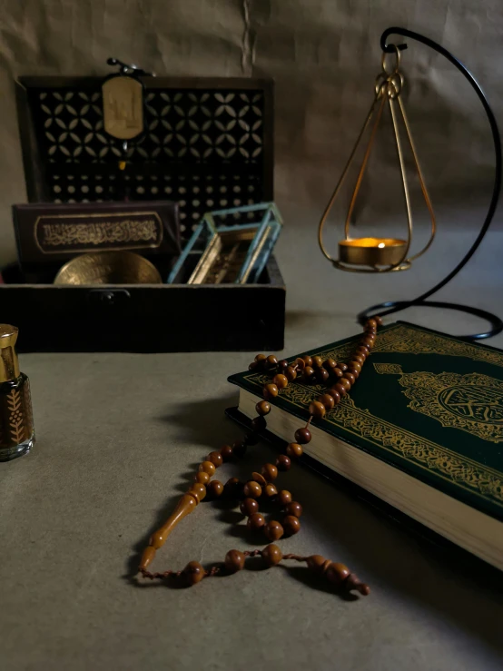 a book sitting on top of a table next to a candle, a still life, inspired by Osman Hamdi Bey, pexels contest winner, hurufiyya, mosque interior, brown, pose 4 of 1 6, panorama shot