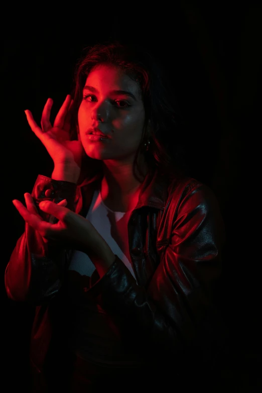 a woman in a leather jacket holding a cell phone, an album cover, inspired by Elsa Bleda, pexels, glowing hands, menacing pose, black and red colors, infp young woman