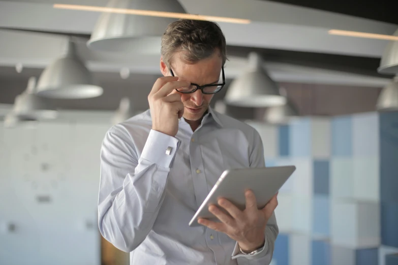 a man holding a tablet and talking on a cell phone, wearing reading glasses, sean mcloughlin, it specialist, thumbnail