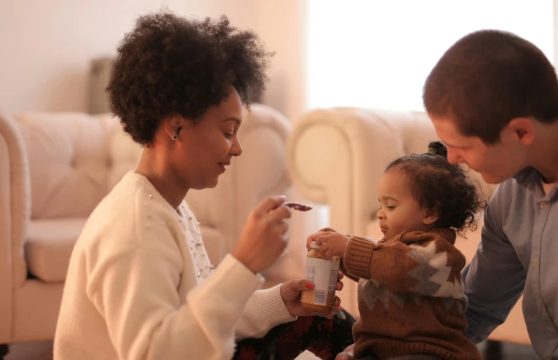 a man and a woman feeding a baby, pexels, realism, light skinned african young girl, drinking cough syrup, cereal, slide show