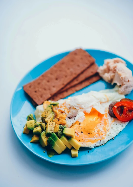 a blue plate topped with a fried egg next to crackers, pexels, happening, avacado dream, vibrantly colored, profile image, 10k