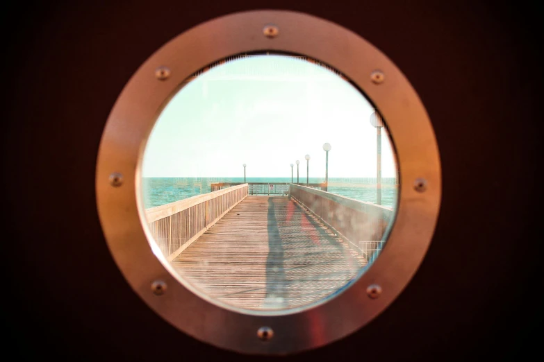 a view of a pier through a porthole, unsplash, visual art, brown, refractive optics, eyelevel perspective image