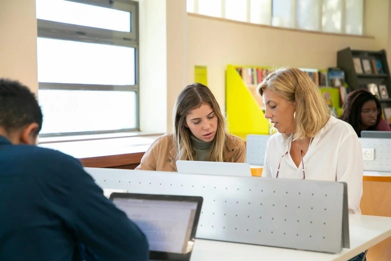 a group of people sitting at a table with laptops, by Jacqui Morgan, unsplash, academic art, backlit, woman, private school, low quality photo