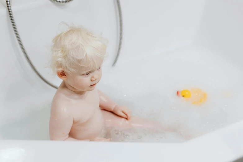 a baby sitting in a bathtub with a rubber duck, by Emma Andijewska, pexels, albino white pale skin, thumbnail, soap bubbles, a blond