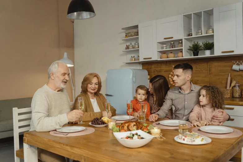 a group of people sitting at a table with plates of food, a picture