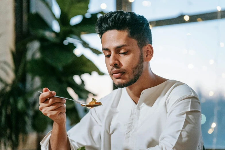 a man sitting at a table with a plate of food, pexels contest winner, middle eastern skin, spoon placed, avatar image, wearing a light shirt