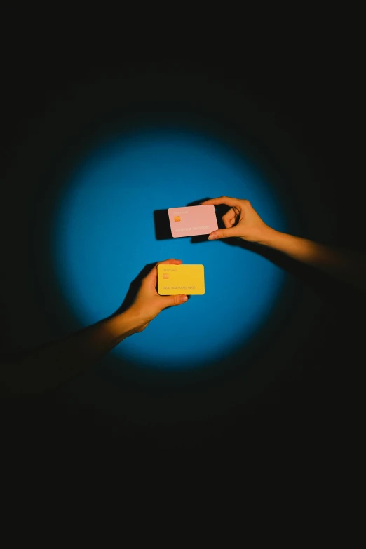 two people holding up their cell phones in the dark, an album cover, by Adam Chmielowski, conceptual art, split - complementary - colors, focus on card, color blocks, yellow and blue
