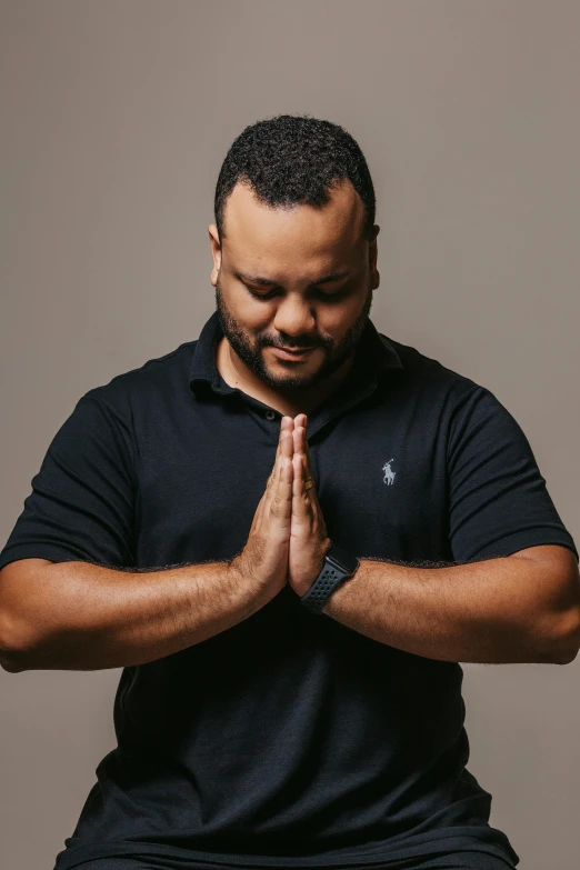 a man in a black shirt is praying, an album cover, inspired by Samuel Silva, unsplash, rubenesque, arms extended, professional picture, yoga