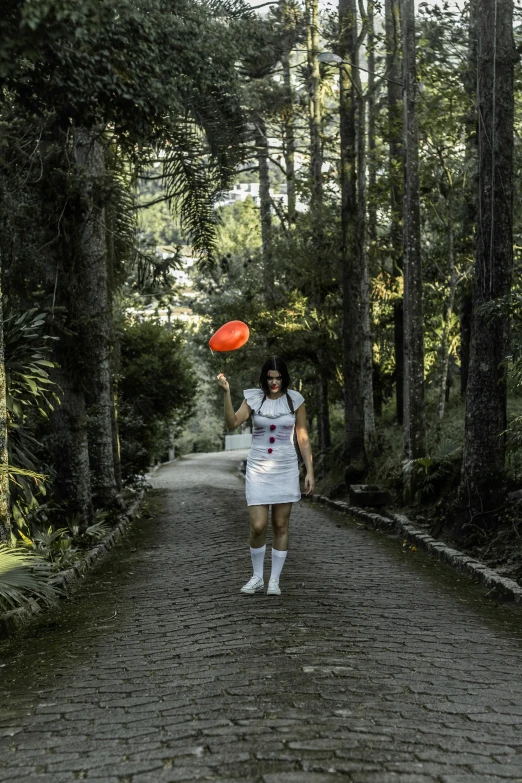 a woman in a white dress holding a red frisbee, inspired by Alice Prin, pexels contest winner, las pozas, full body with costume, coraline, garden road