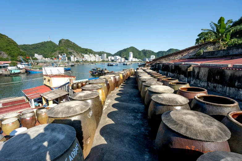 a row of barrels sitting next to a body of water, pexels contest winner, nagasaki, vietnam, maple syrup sea, harbour