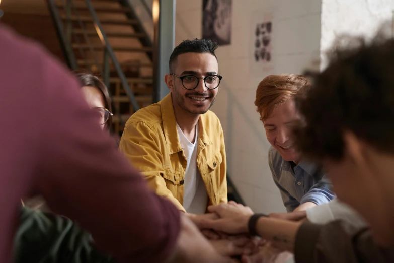 a group of people sitting around a table, trending on pexels, antipodeans, smiling man, hands pressed together in bow, avatar image