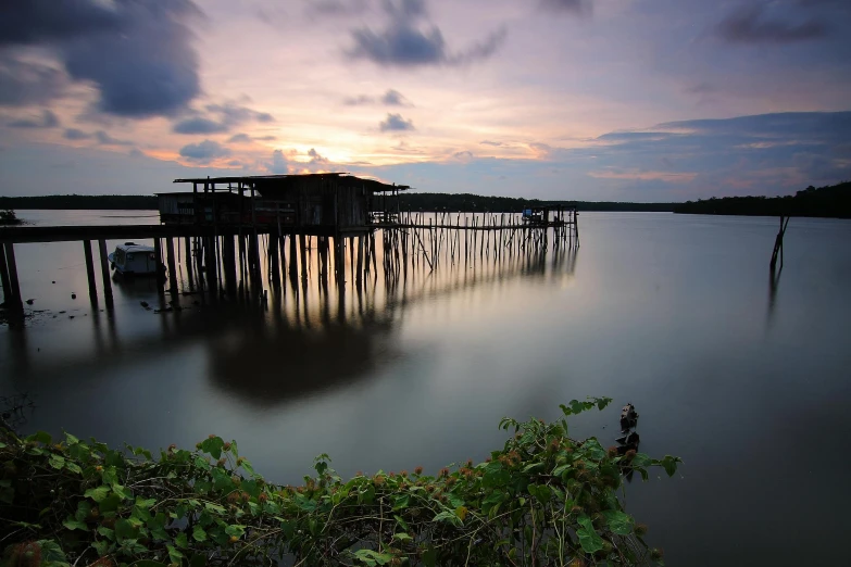 a dock in the middle of a body of water, hurufiyya, dusk setting, ramil sunga, old lumber mill remains, singapore