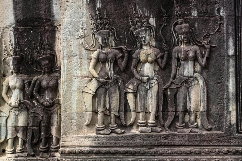 a group of statues on the side of a building, angkor wat, beautiful women, intricate image, three women