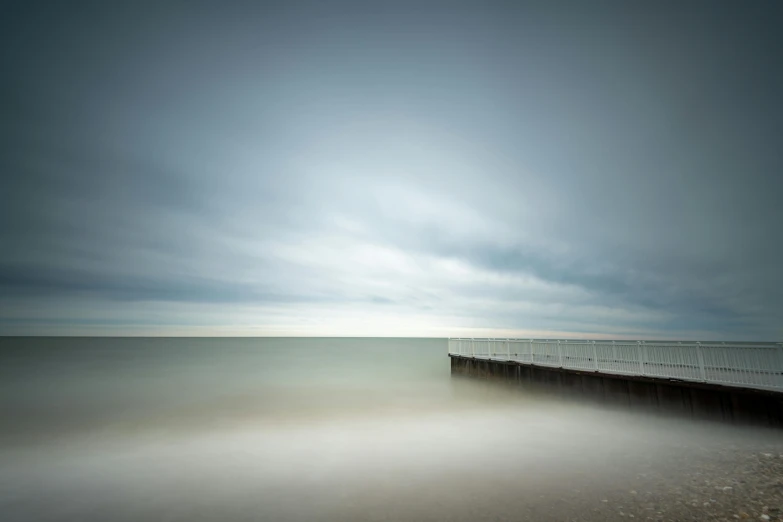 a long exposure photograph of a pier on a cloudy day, by Andrew Geddes, minimalism, medium format. soft light, dramatic ”