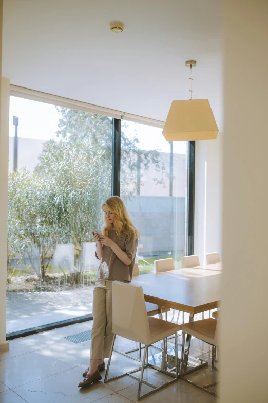 a woman sitting at a table looking at her cell phone, modernism, passive house, square, translucent, high quality image