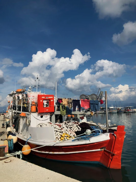 a red and white boat sitting on top of a body of water, fish market, skies, profile image, in the center of the image