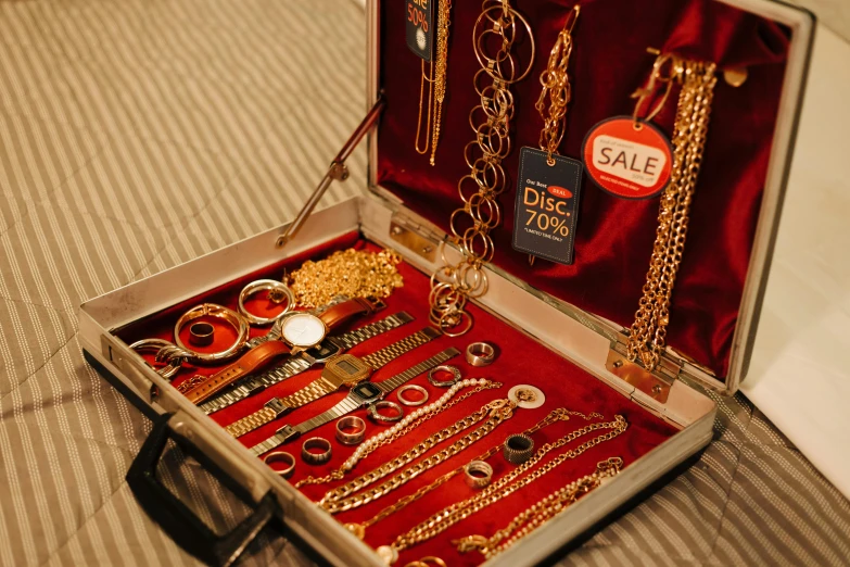 a suitcase filled with jewelry sitting on top of a bed, pexels contest winner, assemblage, gold and red metal, jewelry display, from the 7 0 s, gold chain