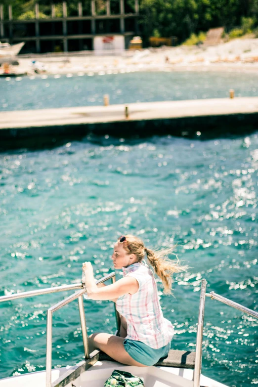 a woman sitting on the bow of a boat, by Julia Pishtar, overexposed sunlight, turquoise water, standing on a bridge, down there