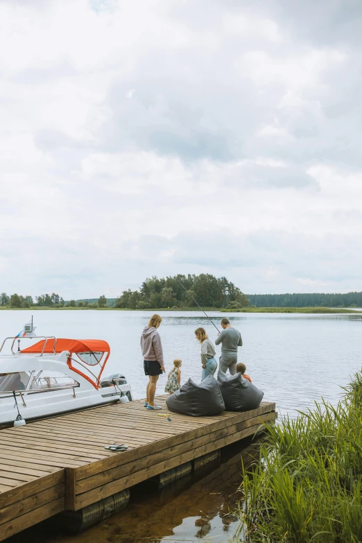 a group of people standing on a dock next to a body of water, finland, tubing, fishing boat, beaching