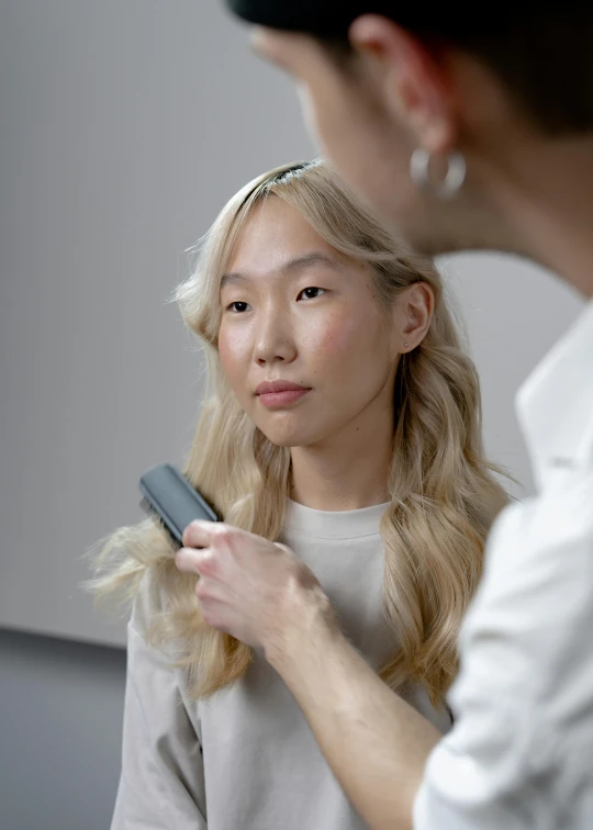 a woman is combing another woman's hair, inspired by Kim Tschang Yeul, platinum blond, mit technology review, gemma chan, holding brush