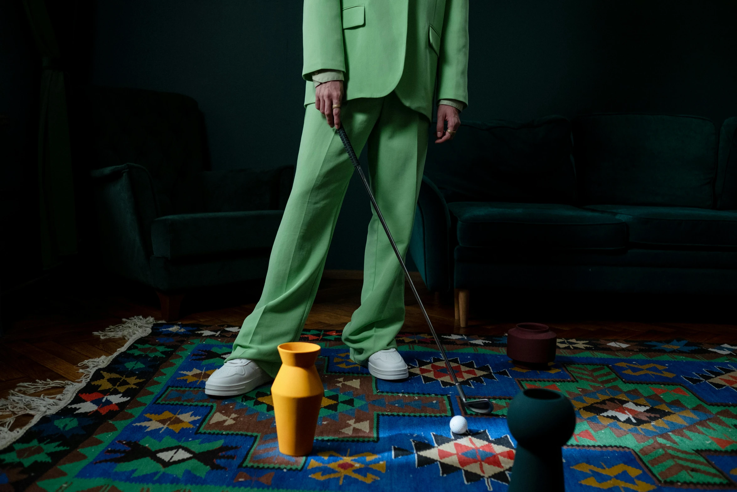 a man in a green suit holding a golf club, by Emma Andijewska, magic realism, dezeen showroom, cups and balls, in house, opening shot