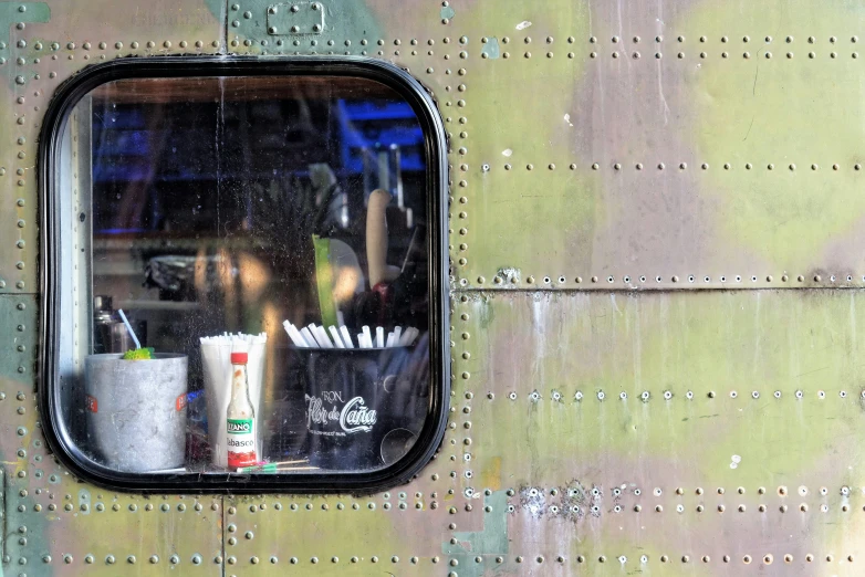 a close up of a window on a plane, inspired by Vivian Maier, unsplash, photorealism, metal with graffiti on the side, american canteen, choo choo, spaceship being repaired