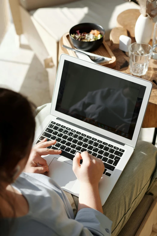 a woman sitting on a couch using a laptop, trending on pexels, high angle close up shot, lawther sit at table playing dnd, natural light outside, thumbnail