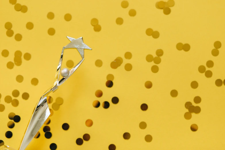 a piece of paper sitting on top of a table, by Julia Pishtar, pexels contest winner, magic realism, metallic scepter, tiny stars, yellow background, celebration