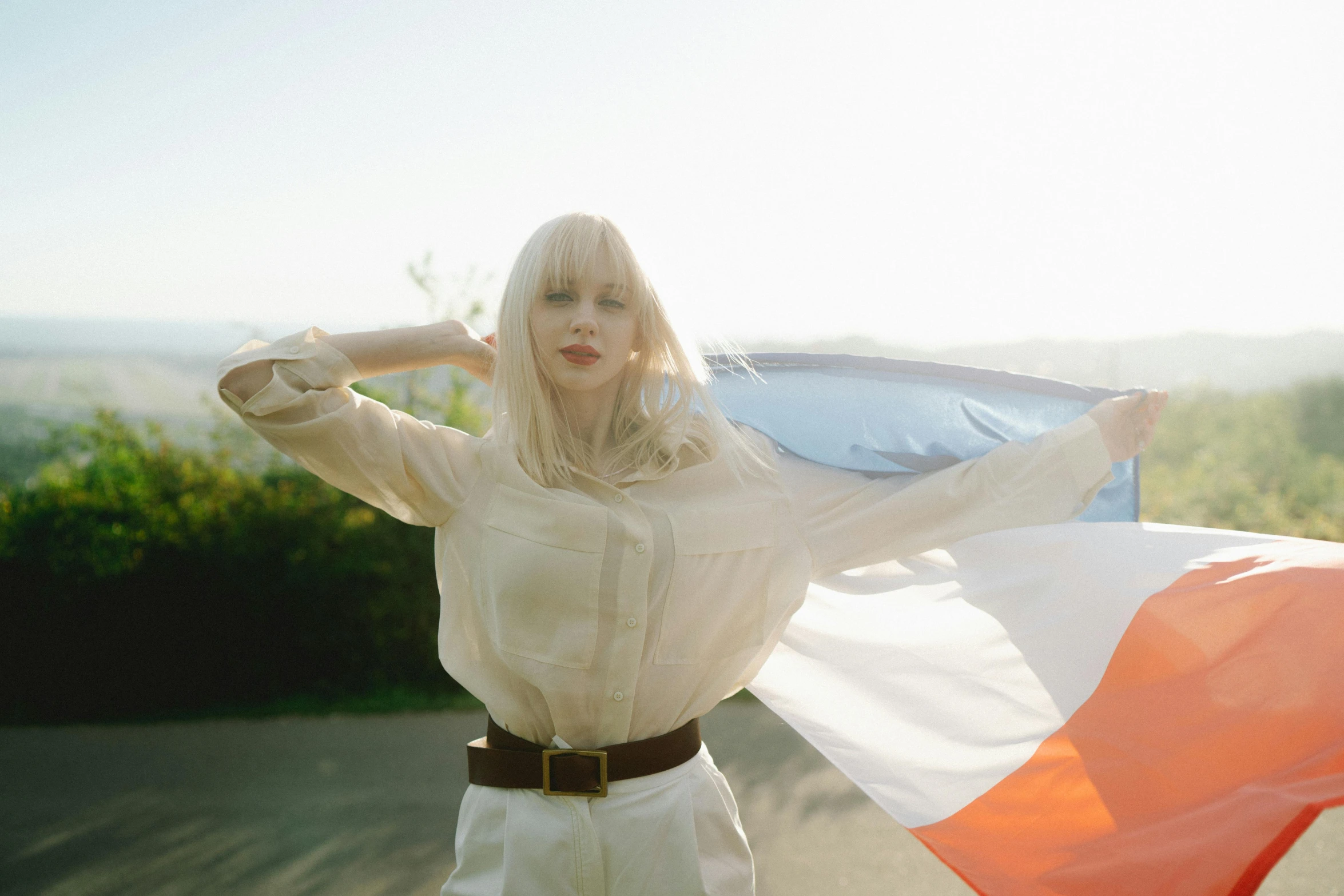 a woman holding an orange, white and blue flag, an album cover, inspired by Elsa Bleda, renaissance, long white hair and bangs, pale beige sky, france, press shot