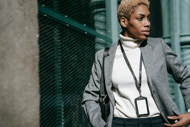 a woman standing with her hands in her pockets, trending on pexels, bauhaus, wearing a turtleneck and jacket, female lawyer, cyber necklace, beautiful city black woman only