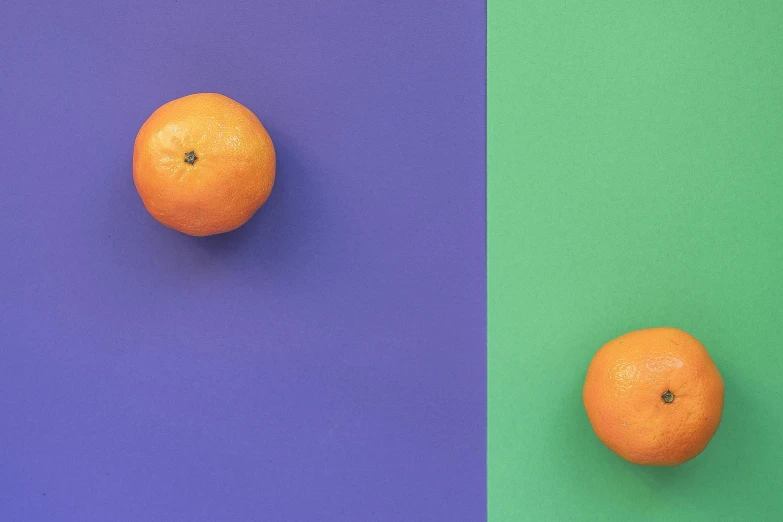 a couple of oranges sitting on top of a blue and green surface, inspired by Christo, trending on pexels, postminimalism, second colours - purple, diptych, multicoloured, fruit