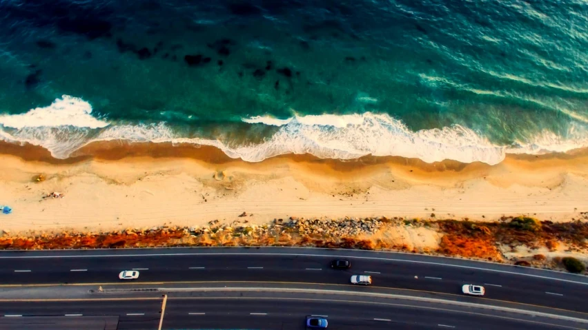 a group of cars driving down a road next to the ocean, by Niko Henrichon, pexels contest winner, renaissance, sand and sea, los angelos, flattened, manly