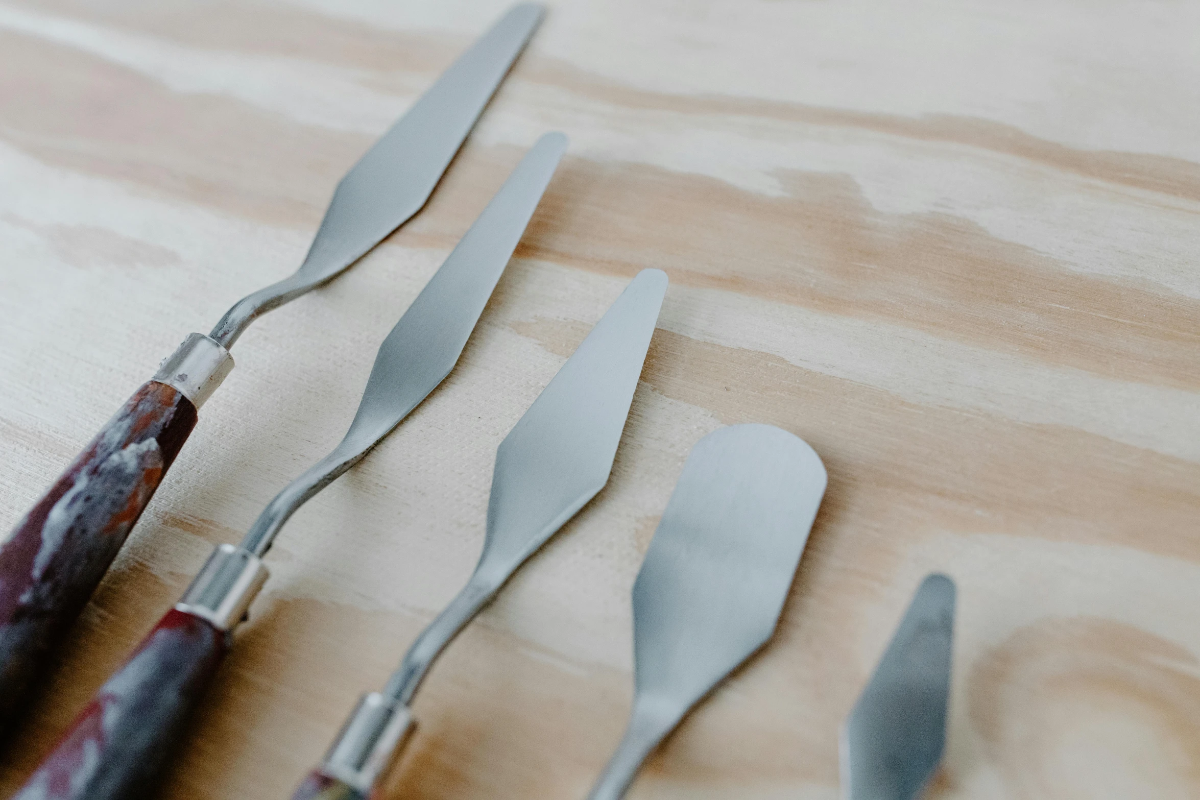 a bunch of knives sitting on top of a wooden table, trending on pexels, process art, spatula, miniature product photo, dessert, on a pale background