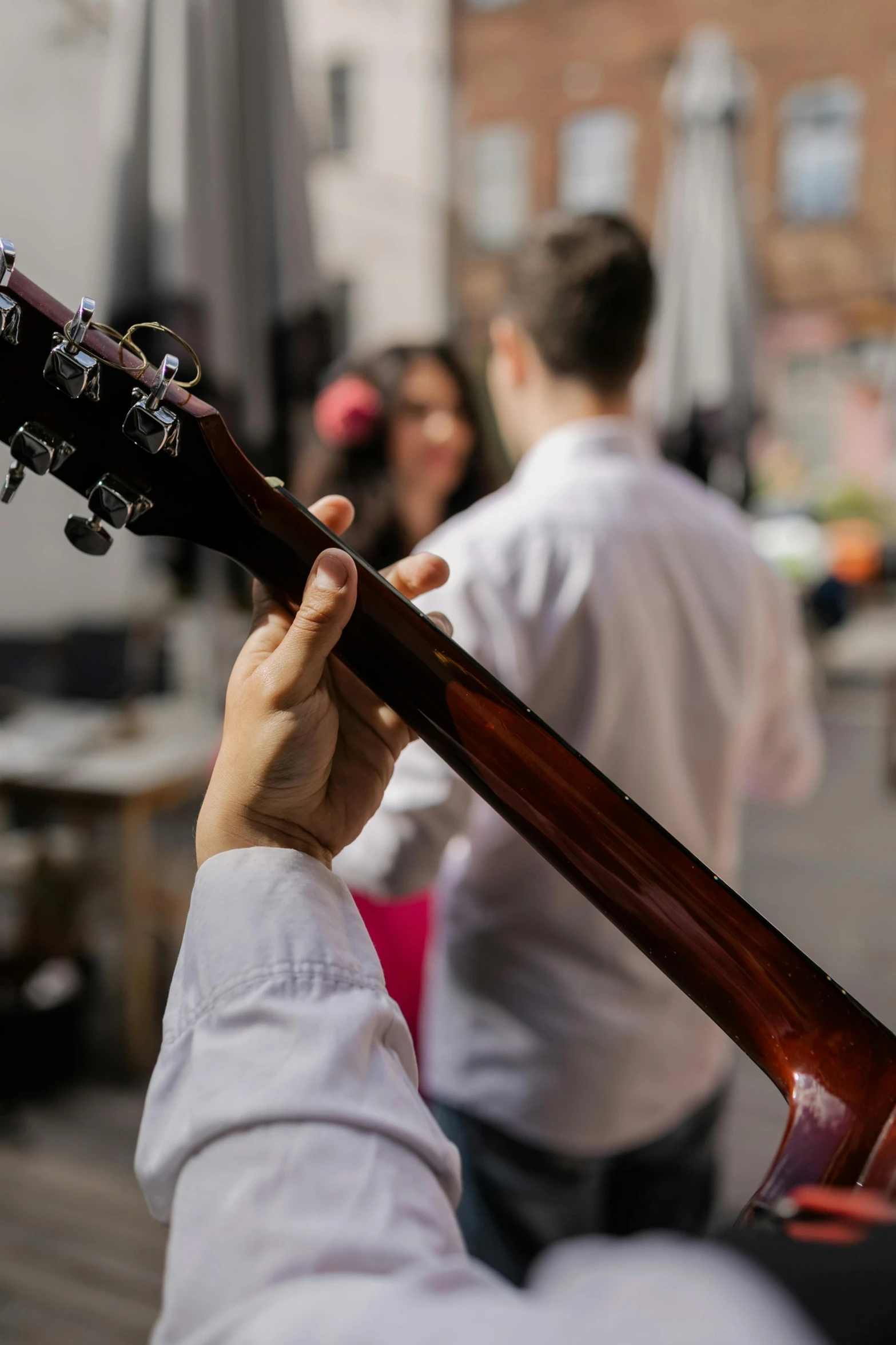 a close up of a person playing a guitar, people dancing in background, in a workshop, facing away, vendors