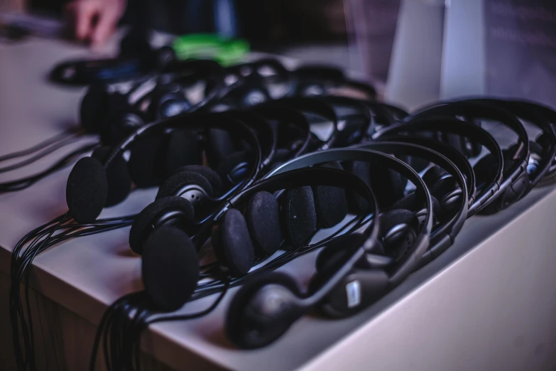 a bunch of headphones sitting on top of a table, by Nina Hamnett, unsplash, computer art, in an call centre office, avatar image, straps, theatre equipment