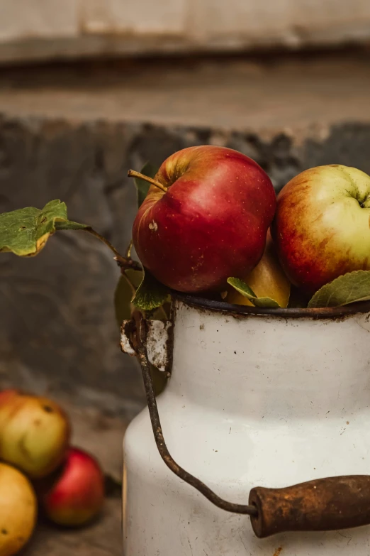 a bucket filled with apples sitting on top of a table, a still life, unsplash, close - up photo, background image, antique renewal, milk