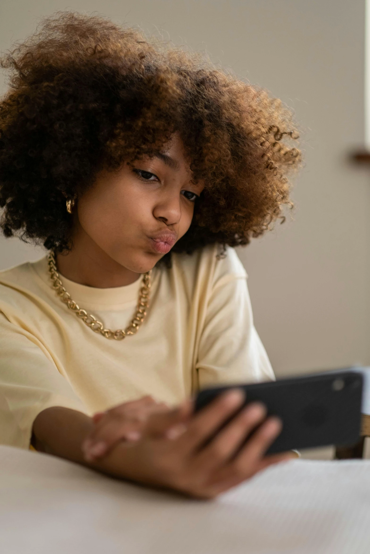 a woman sitting at a table using a cell phone, rated t for teen, essence, gen z, looking at monitor